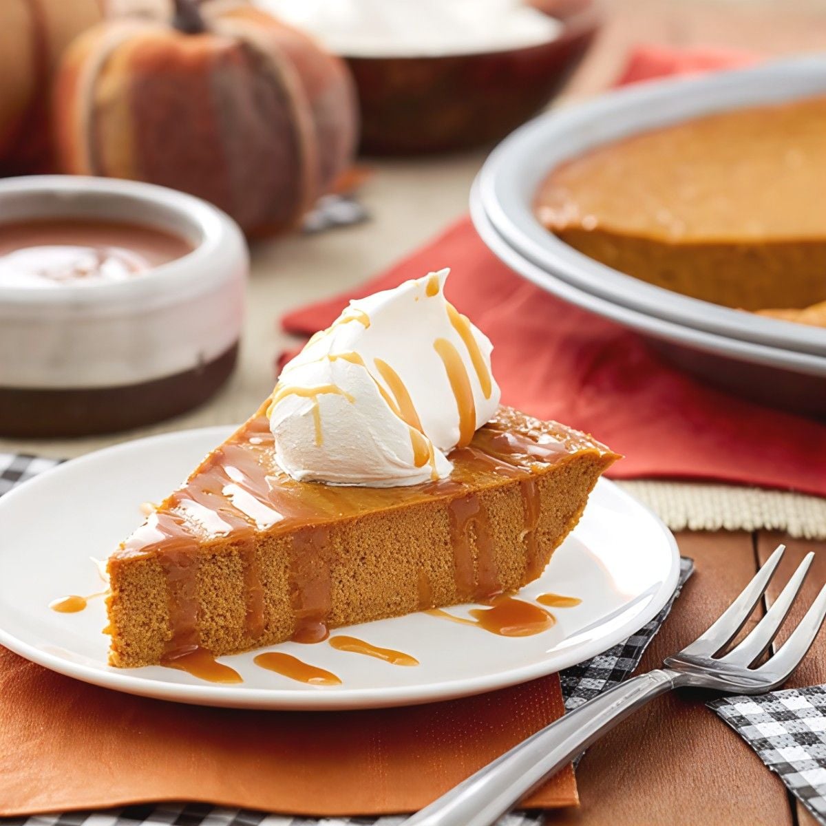 A slice of crustless gluten-free pumpkin pie topped with whipped cream and caramel sauce, perfect for gluten-free Thanksgiving desserts.