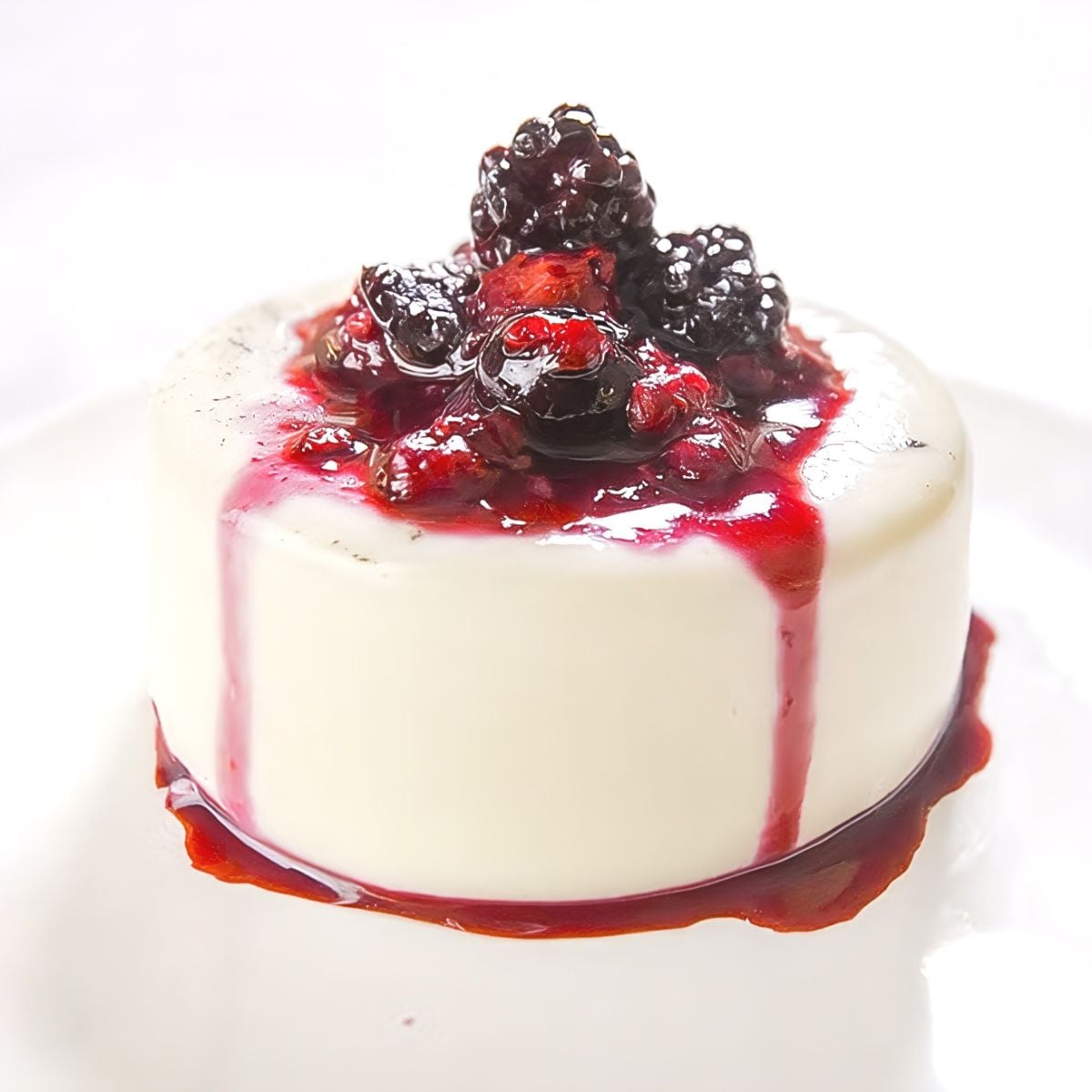 A creamy vanilla panna cotta topped with fresh blackberry sauce, ideal for gluten-free Thanksgiving desserts.