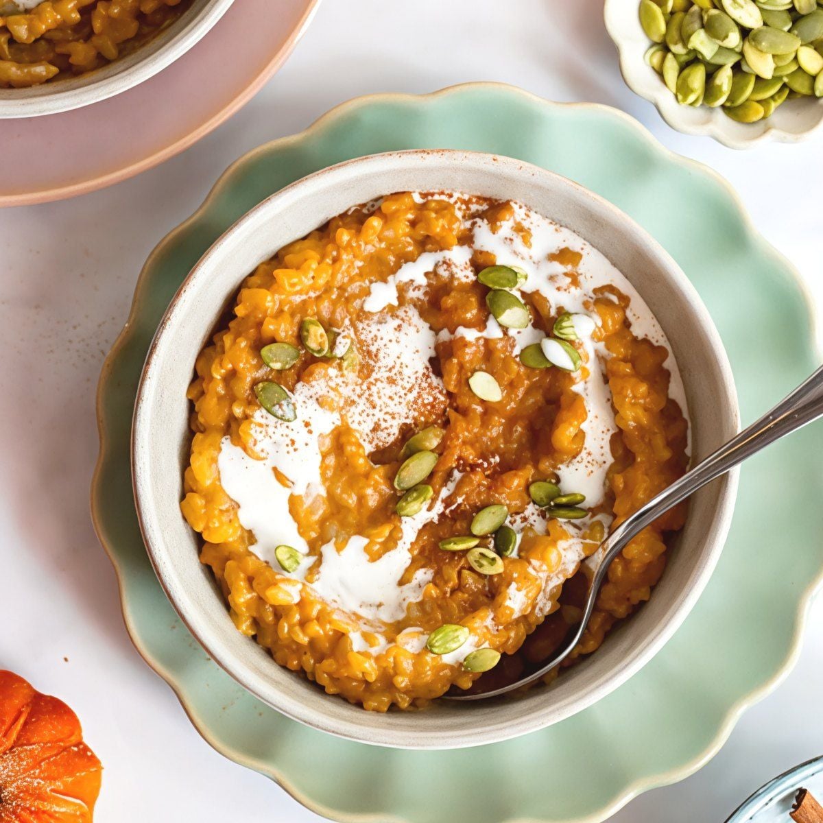 A bowl of creamy pumpkin rice pudding topped with cream, pumpkin seeds, and cinnamon, perfect for gluten-free Thanksgiving desserts