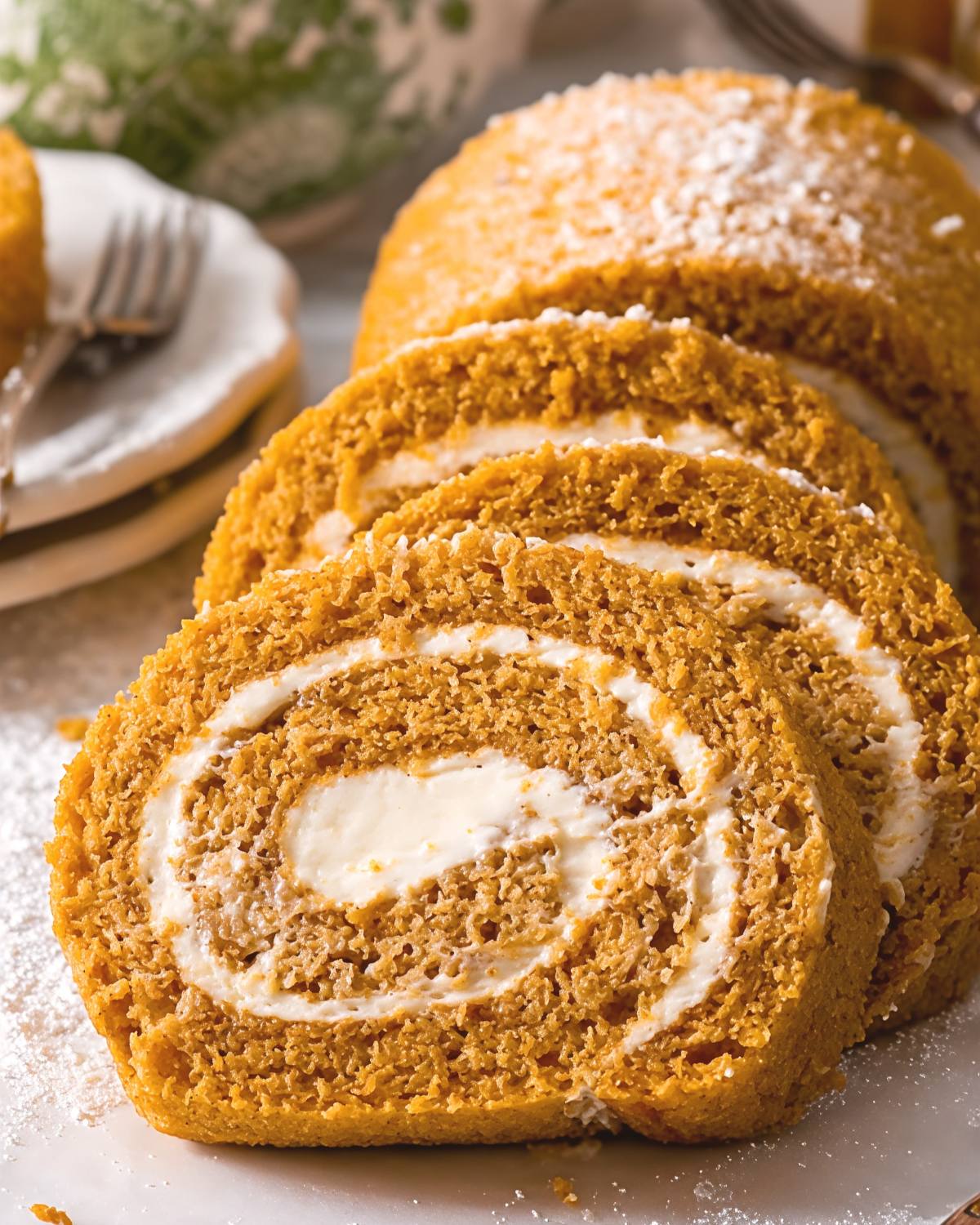 Sliced homemade gluten-free pumpkin roll with cream cheese filling, perfect for gluten-free Thanksgiving desserts.