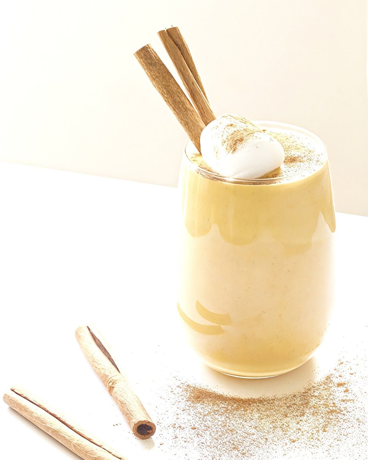 A creamy pumpkin spice smoothie topped with whipped cream and cinnamon sticks, perfect for gluten-free Thanksgiving desserts.