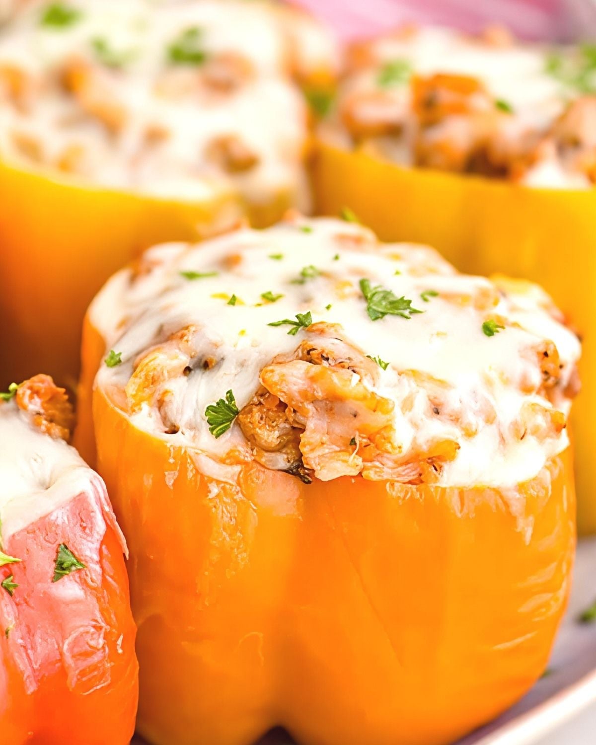 Crockpot stuffed orange bell peppers filled with meat and rice, topped with melted mozzarella cheese and chopped fresh parsley.