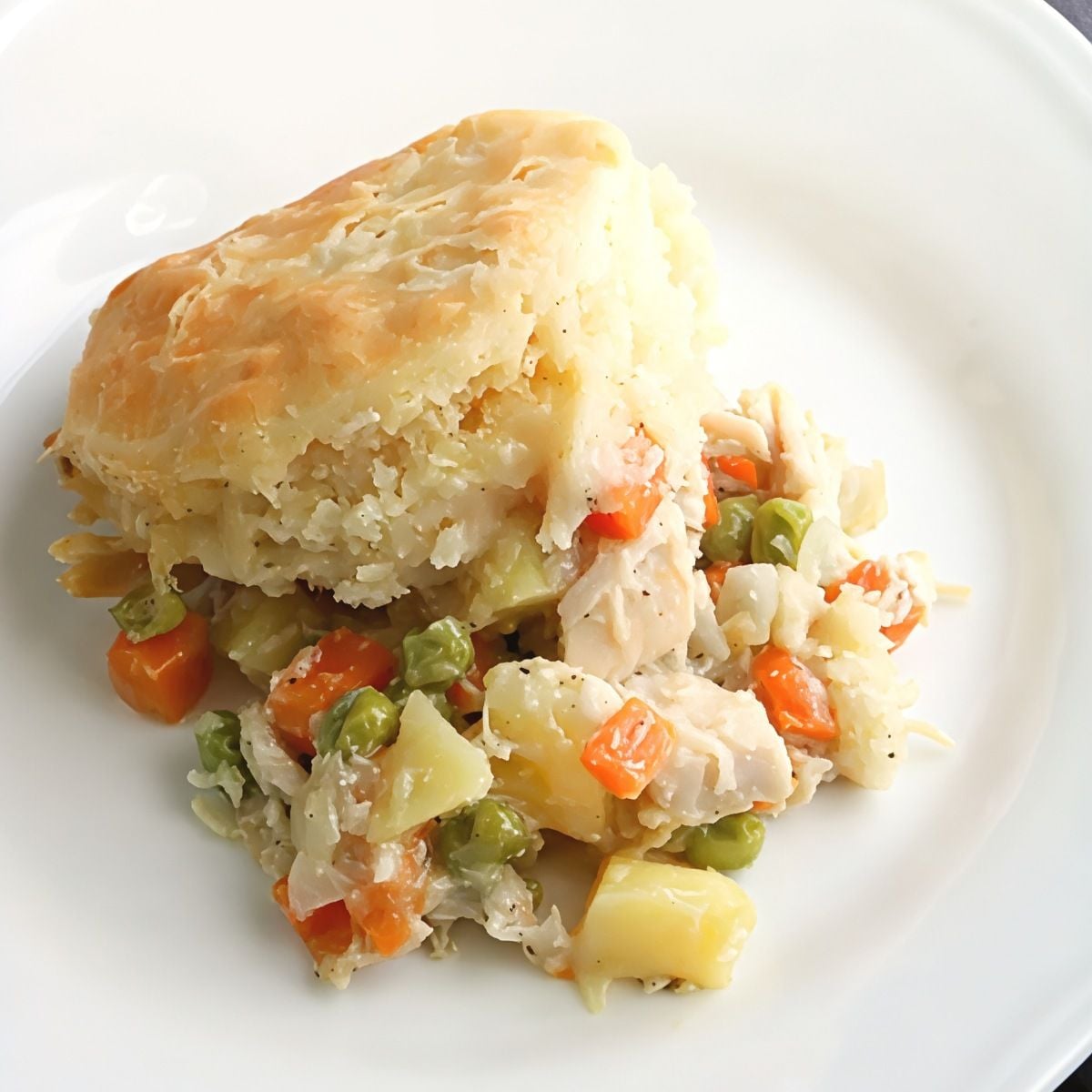 Savory leftover turkey breast pot pie filled with mixed vegetables and served with a flaky golden biscuit topping on a white plate.
