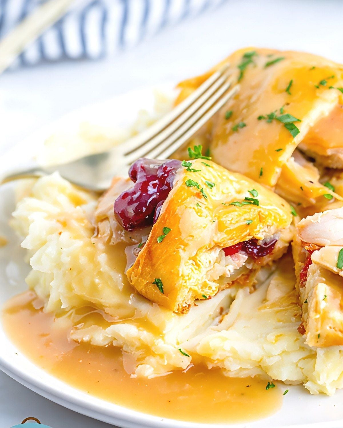 Golden baked leftover turkey and stuffing bundles served over creamy mashed potatoes with gravy and cranberry sauce.