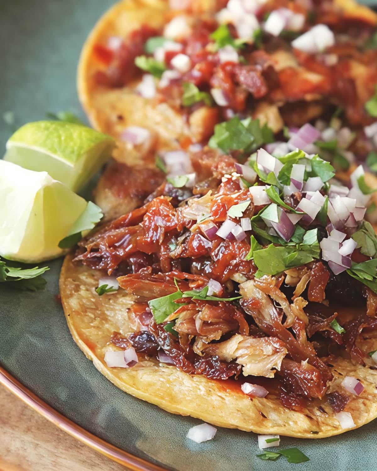 Crispy leftover turkey carnitas tacos garnished with diced onions, fresh cilantro, salsa, and lime wedges on a plate, ideal for flavorful leftover turkey recipes.