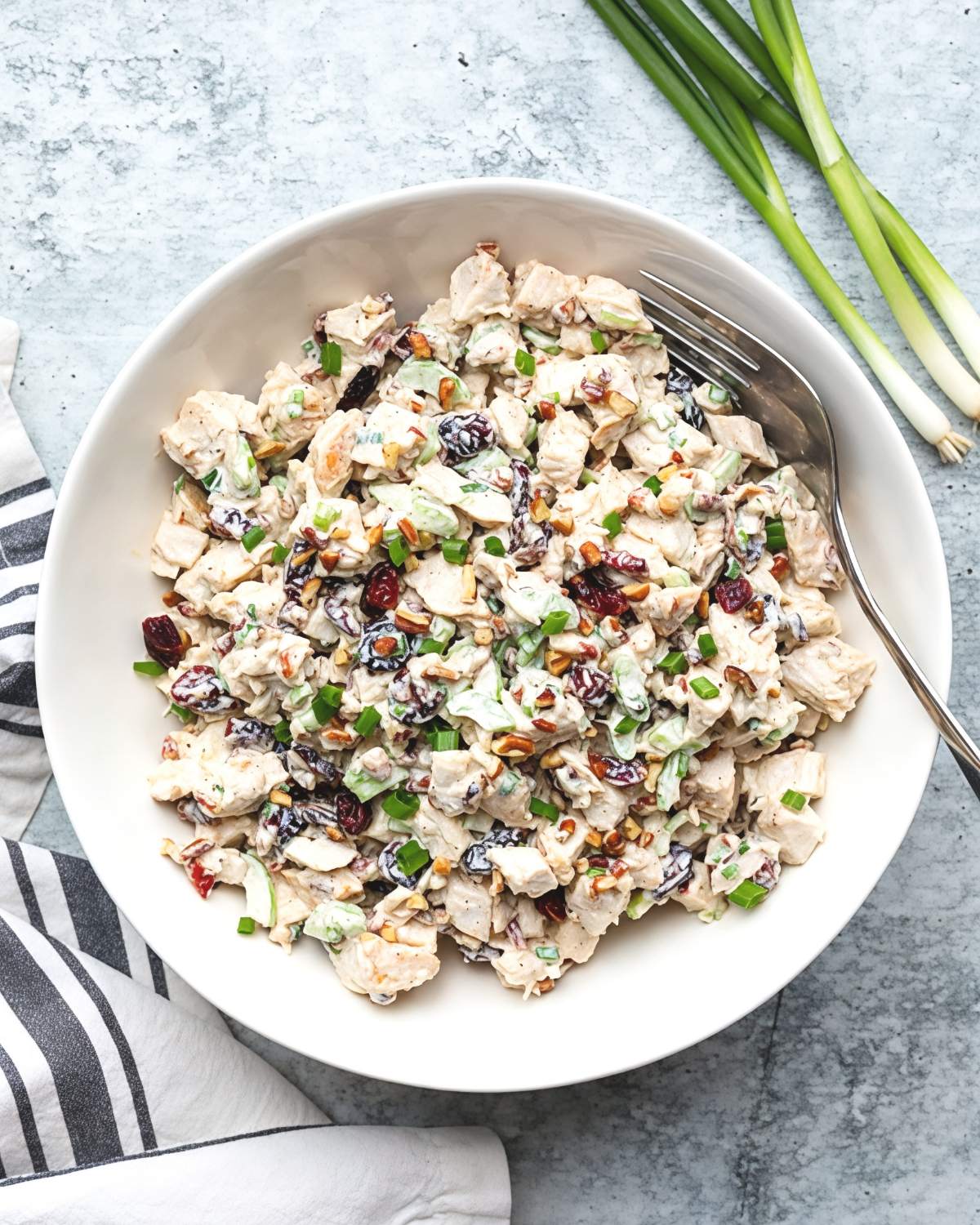 Creamy leftover turkey salad tossed with dried cranberries, chopped nuts, green onions, and celery served in a white bowl, perfect for easy leftover turkey recipes.