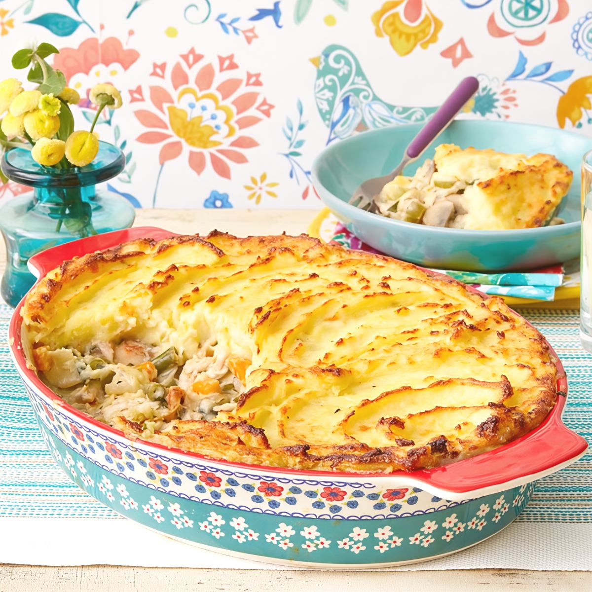 Golden baked leftover turkey shepherd's pie topped with creamy mashed potatoes in a colorful baking dish.