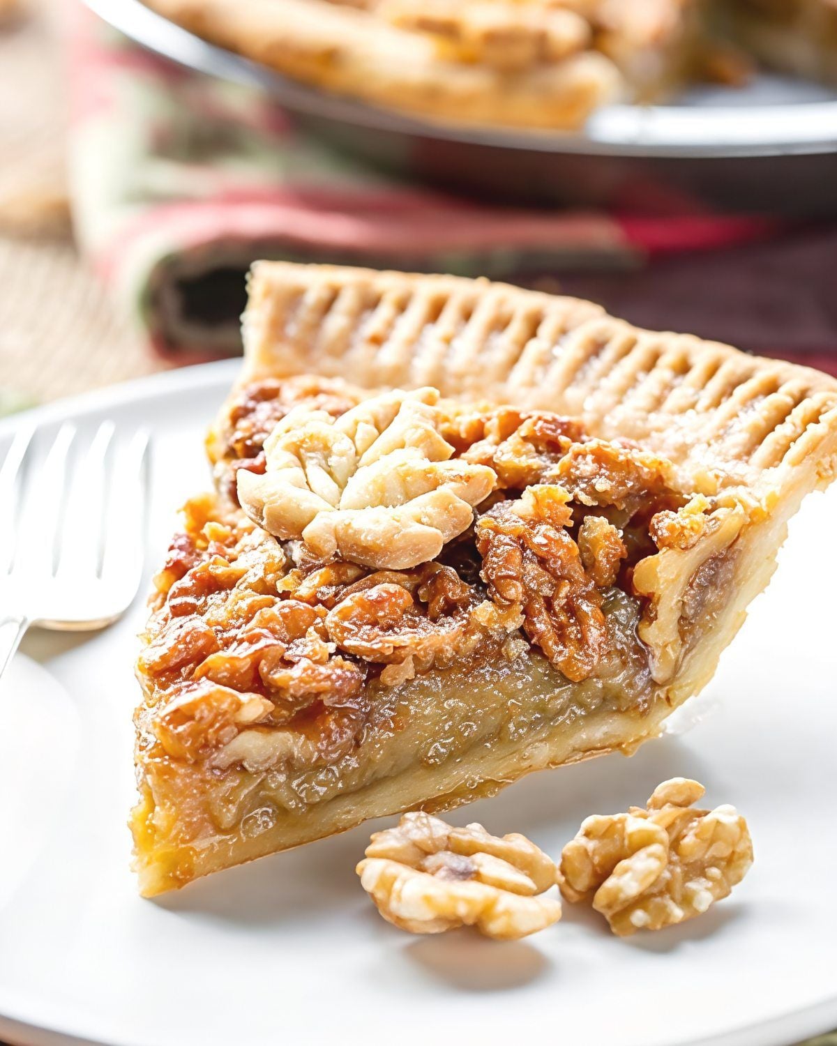 A slice of decadent maple walnut pie featuring a crimped pastry crust, rich maple filling, and crunchy toasted walnuts topped with decorative pie crust cutouts.