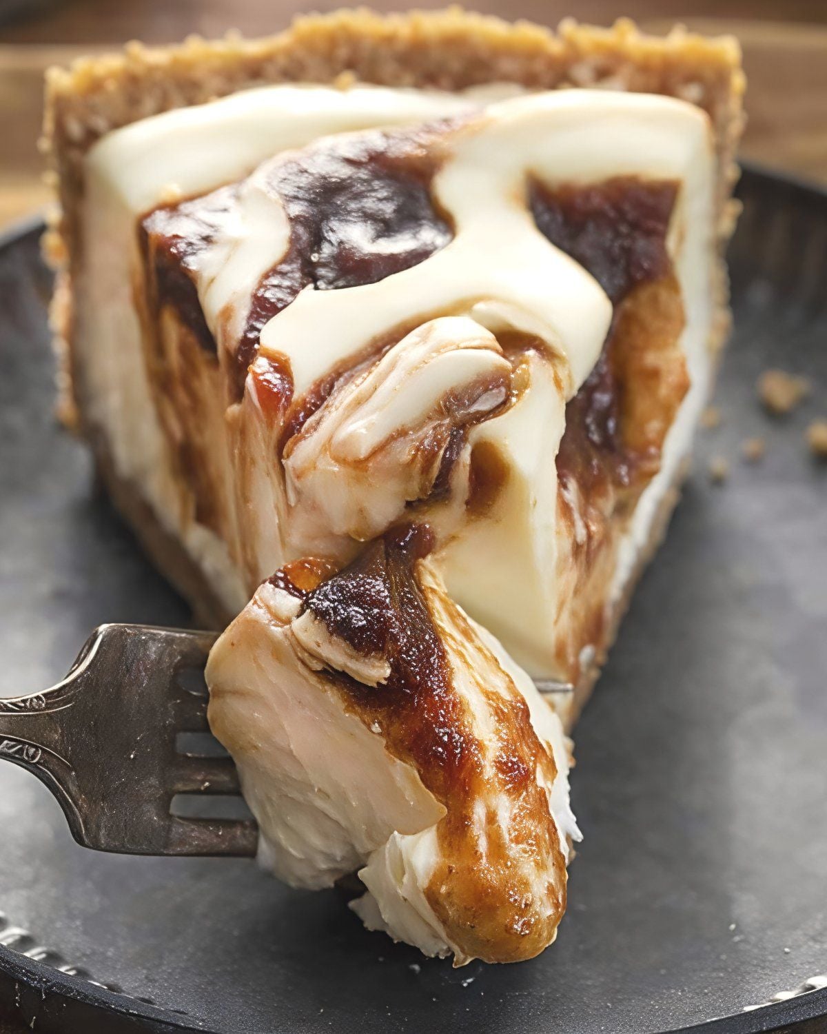 A slice of smooth no-bake apple butter cheesecake with a graham cracker crust and rich spiced apple butter swirled throughout, served with a fork taking a bite