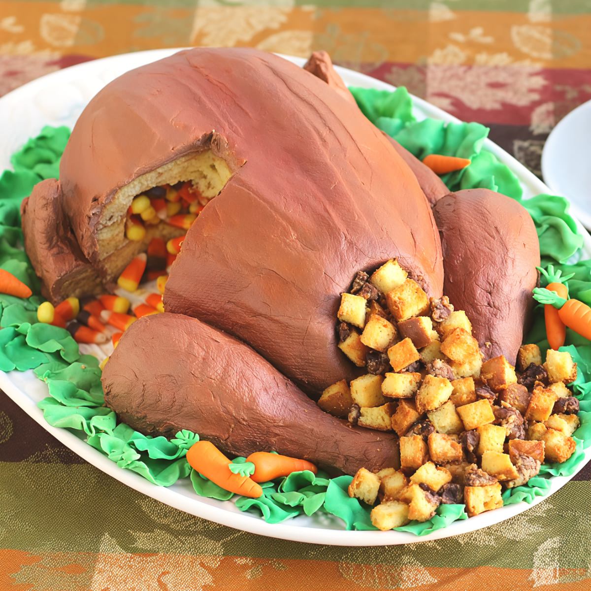 Realistic roasted turkey cake stuffed with cake croutons and candy corn fillings, served on a platter with green lettuce frosting and tiny marzipan carrots.