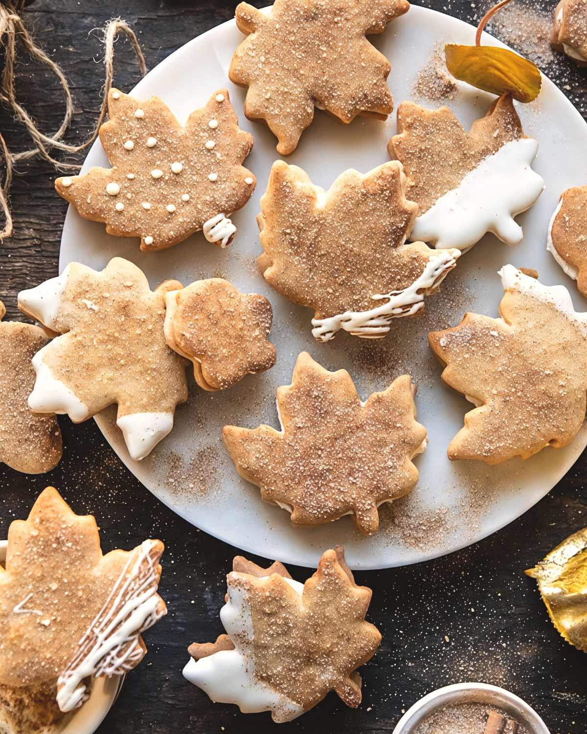 These festive Thanksgiving cookies are shaped like autumn leaves and feature cozy chai spices with rich browned butter frosting on a white plate.