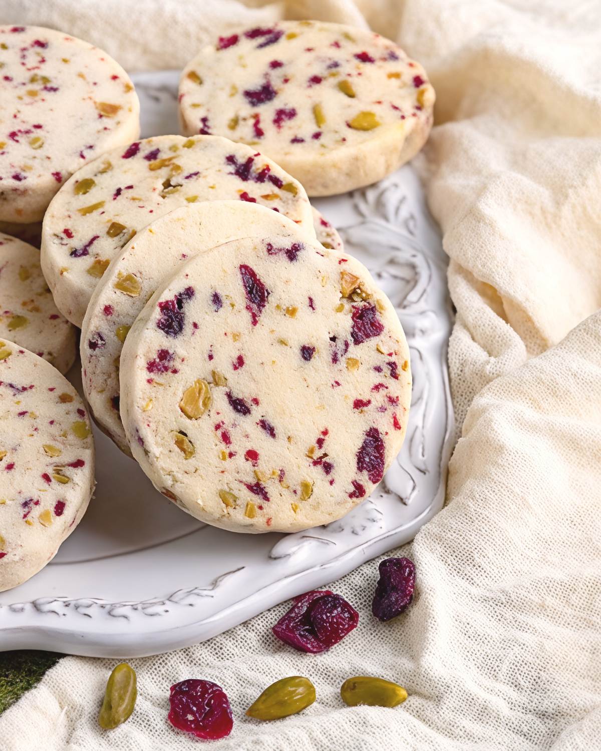 These festive Thanksgiving cookies feature buttery shortbread packed with vibrant red cranberries and crunchy green pistachios, served on a light blue decorative plate.