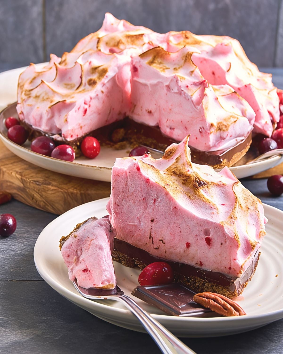 Slice of cranberry chocolate meringue pie with a pecan crust topped with toasted pink meringue, perfect for Thanksgiving dessert ideas.