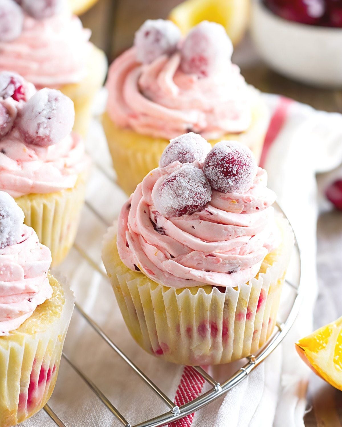 Fluffy cranberry orange cupcakes topped with pink swirl frosting and sugared cranberries, perfect for festive Thanksgiving dessert ideas.