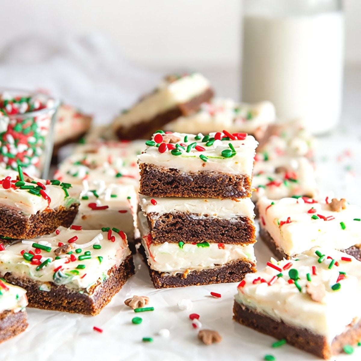 Stacked chewy gingerbread cookie bars topped with creamy white frosting and festive red and green sprinkles, perfect for Thanksgiving dessert ideas.