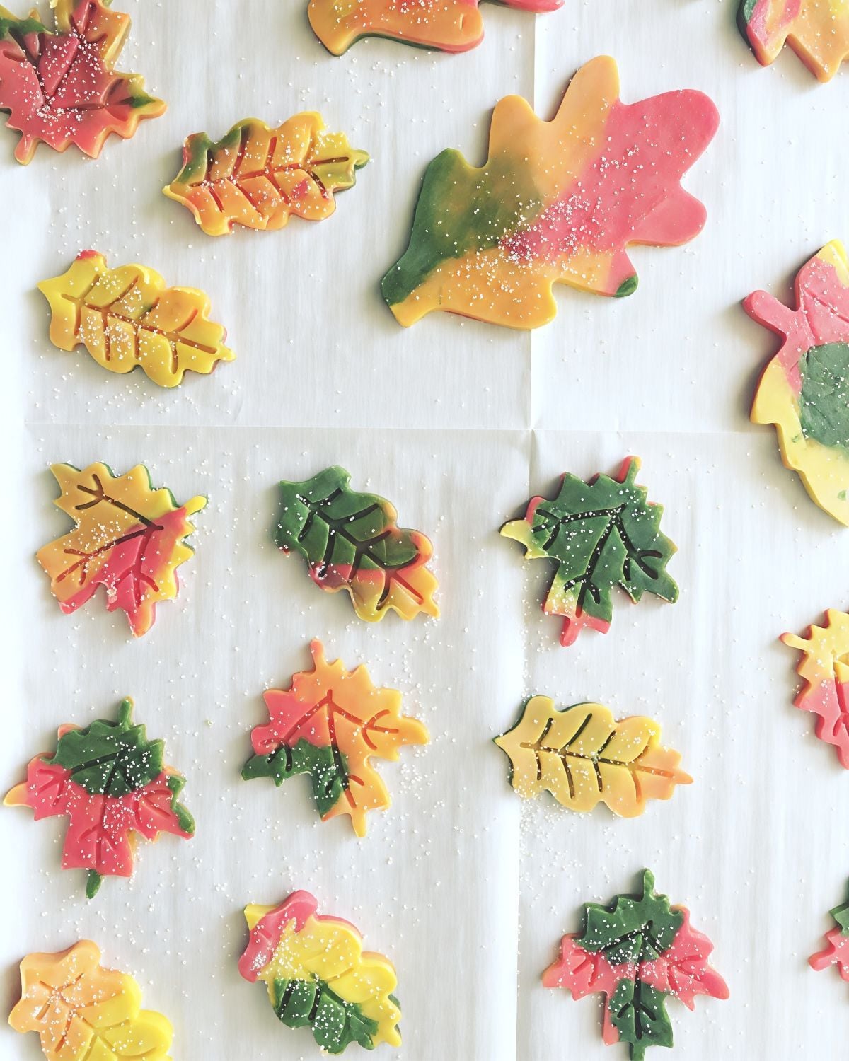 Colorful autumn leaf sugar cookies decorated in red, yellow, and green hues with sparkling sugar, ideal for Thanksgiving dessert ideas.