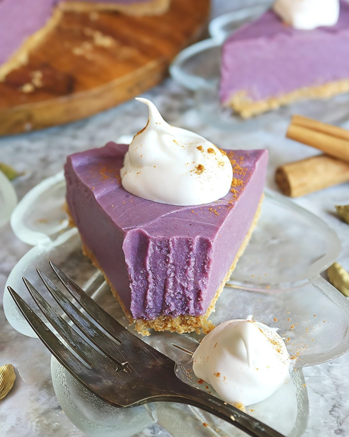 Slice of no-bake vegan purple sweet potato pie topped with coconut whipped cream and cinnamon, perfect for healthy Thanksgiving dessert ideas.