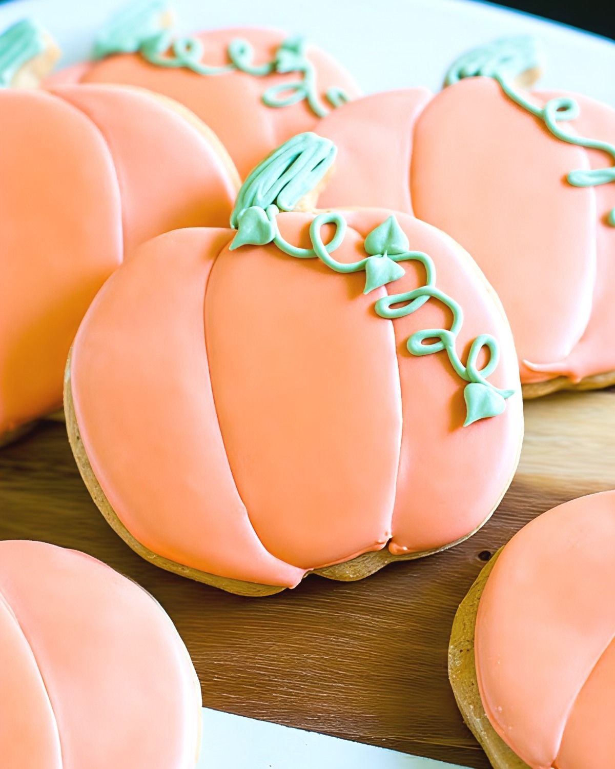 Spiced pumpkin cut-out sugar cookies decorated with light orange royal icing and green icing stems for festive Thanksgiving dessert ideas.