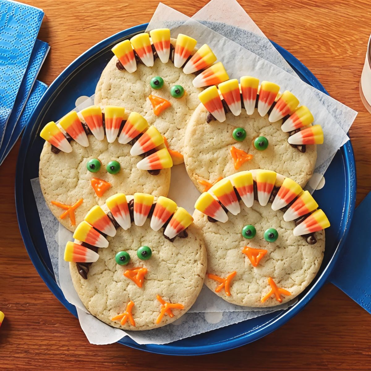 Round Thanksgiving turkey sugar cookies decorated with candy corn feathers, green candy eyes, and orange icing beaks, perfect for festive Thanksgiving dessert ideas.