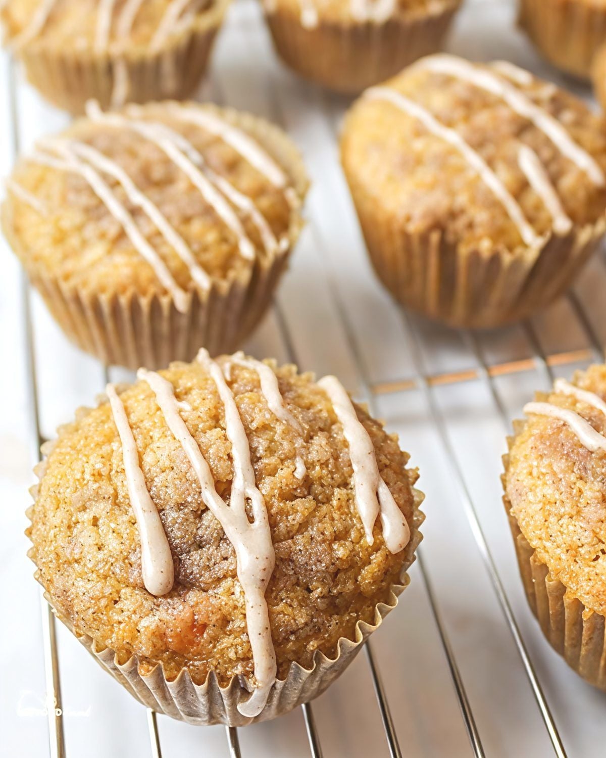 Freshly baked leftover mashed sweet potato muffins with cinnamon drizzle resting on a metal cooling rack.