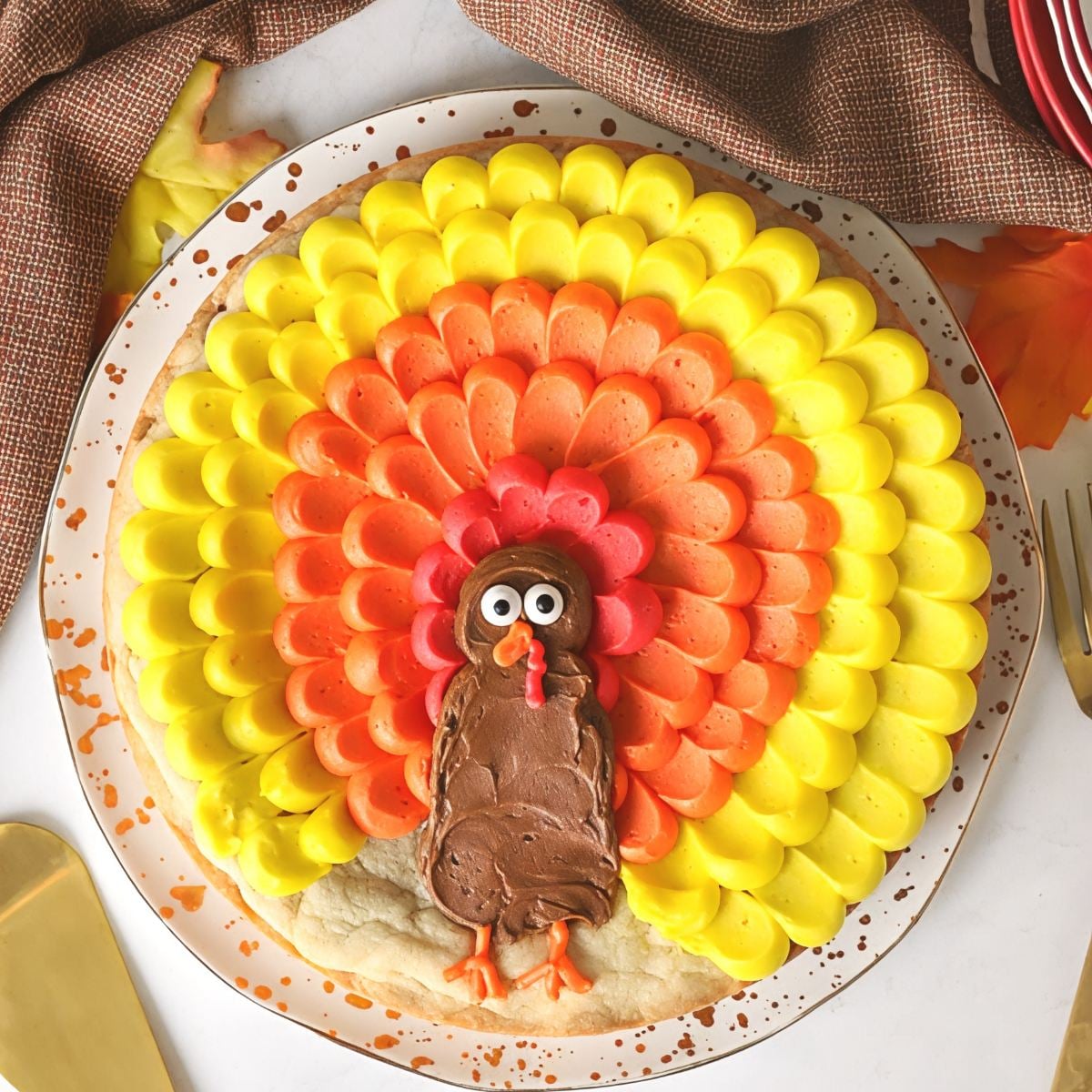 Fun turkey cookie cake decorated with vibrant yellow, orange, and red frosted feathers around a chocolate turkey center.